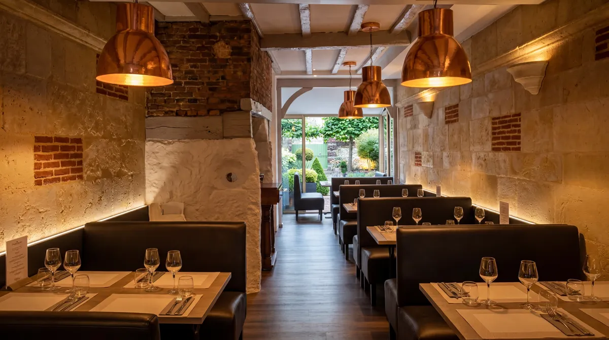 Interieur du restaurant L'Accord Parfait, murs en pierre, poutres apparentes et luminaires cuivre